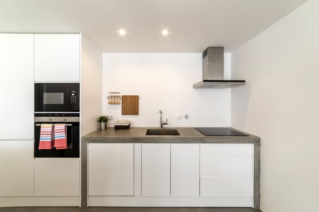 Cocina moderna con encimera gris y muebles blancos instalada en Málaga